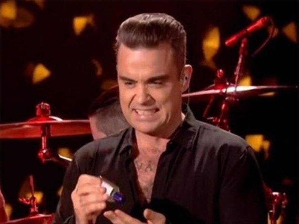 Su cara lo dice todo, Robbie Williams se desinfecta tras tocar a fans